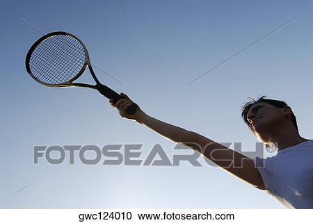 Low angle view of a mid adult woman holding a tennis racket View Large Photo Image Stock Image - Low angle view of a mid adult woman holding a tennis racket. Fotosearch