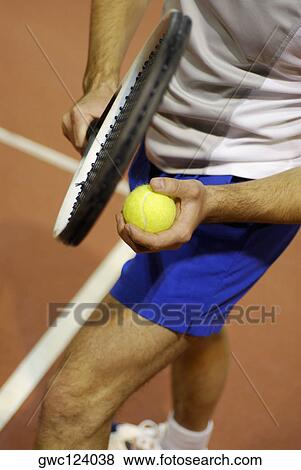 Low section view of a man holding a tennis ball and a tennis racket View Large Photo Image Stock Photo - Low section view of a man holding a tennis ball and a tennis racket. Fotosearch