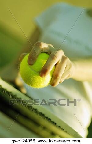 Stock Photograph - Mid section view of a woman holding a tennis ball and a tennis racket. Fotosearch