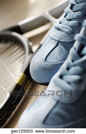Stock Image - Close-up of a pair of sports shoes and a tennis racket. Fotosearch