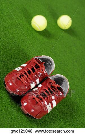 Stock Photo - Close-up of a pair of sports shoes and two tennis balls. Fotosearch