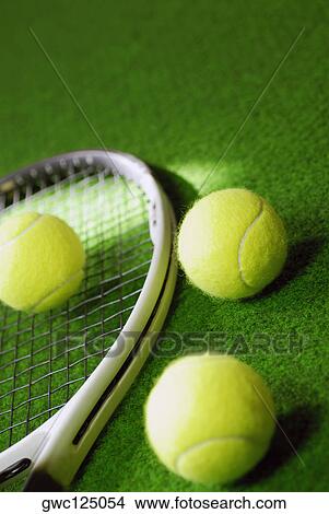 Picture - Close-up of three tennis bowls and a tennis racket. Fotosearch