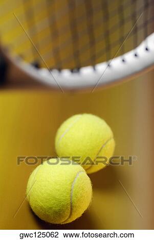 Stock Image - Close-up of two tennis balls with a tennis racket. Fotosearch