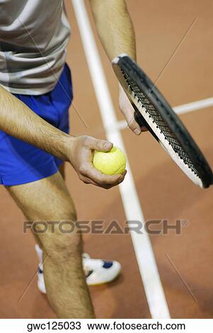 High angle view of a man holding a tennis ball and a tennis racket View Large Photo Image Stock Image - High angle view of a man holding a tennis ball and a tennis racket. Fotosearch