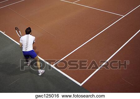 Stock Photograph - High angle view of a man playing tennis. Fotosearch