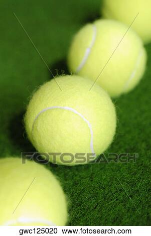 Stock Image - High angle view of four tennis balls in a row. Fotosearch