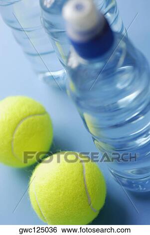 Stock Photograph - High angle view of two tennis balls with three water bottles. Fotosearch