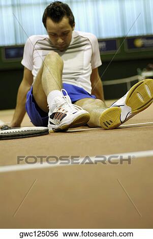 Mid adult man sitting on a tennis court View Large Photo Image Stock Photograph - Mid adult man sitting on a tennis court. Fotosearch
