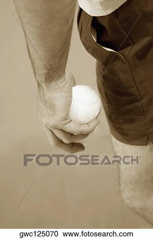 Stock Image - Mid section view of a man holding a tennis ball. Fotosearch