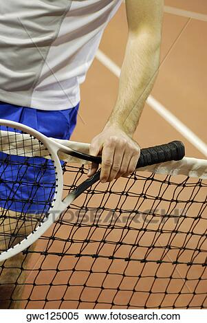 Stock Photography - Mid section view of a man holding a tennis racket. Fotosearch