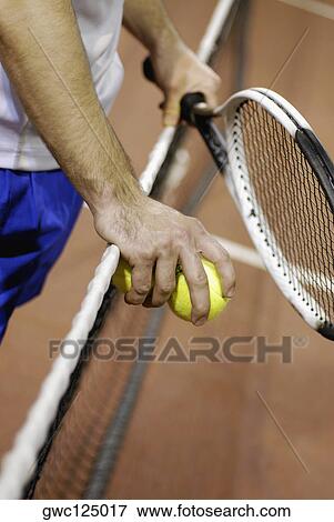 Mid section view of a man holding two tennis balls and a tennis racket View Large Photo Image Stock Photo - Mid section view of a man holding two tennis balls and a tennis racket. Fotosearch