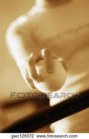 Stock Image - Mid section view of a woman holding a tennis ball. Fotosearch
