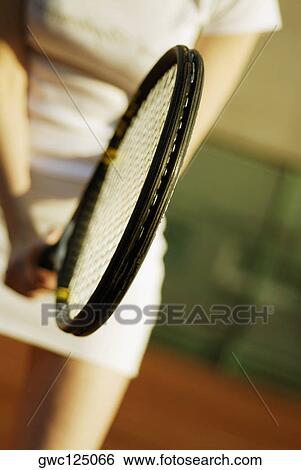 Stock Photograph - Mid section view of a woman holding a tennis racket. Fotosearch
