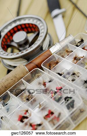 Stock Photo - Close-up of a fishing reel and a fishing rod with fly boxes. Fotosearch