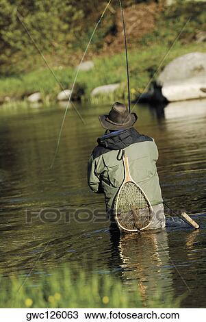 Rear view of a man fishing in the river View Large Photo Image Stock Image - Rear view of a man fishing in the river. Fotosearch