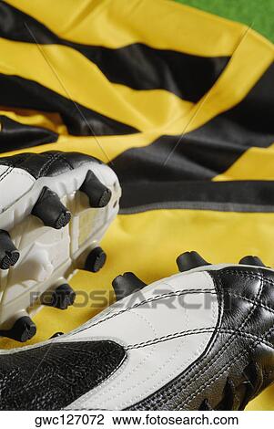 Stock Image - Close-up of a pair of soccer shoes on a soccer t-shirt. Fotosearch