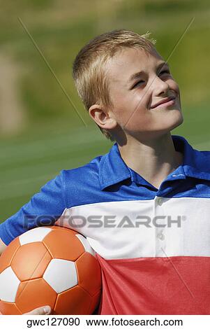 Stock Image - Close-up of a soccer player holding a soccer ball and smiling. Fotosearch