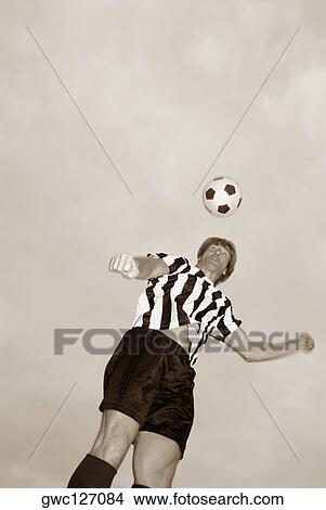 Low angle view of a soccer player heading a soccer ball View Large Photo Image Picture - Low angle view of a soccer player heading a soccer ball. Fotosearch