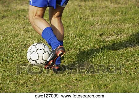 Stock Photo - Low section view of a soccer player dodging a soccer ball. Fotosearch