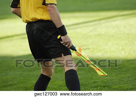 Stock Image - Mid section view of a referee holding a flag. Fotosearch