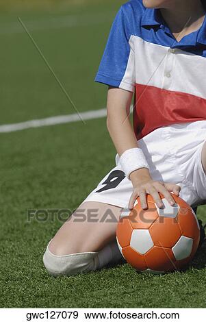 Mid section view of a soccer player kneeling on a soccer field with a soccer ball View Large Photo Image Stock Photo - Mid section view of a soccer player kneeling on a soccer field with a soccer ball. Fotosearch