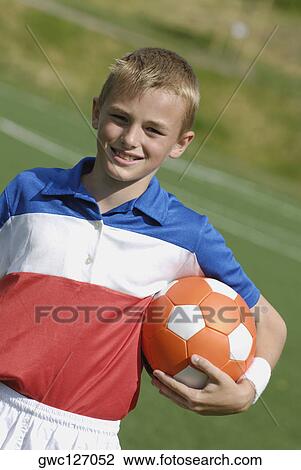 Stock Image - Portrait of a soccer player holding a soccer ball and smiling. Fotosearch