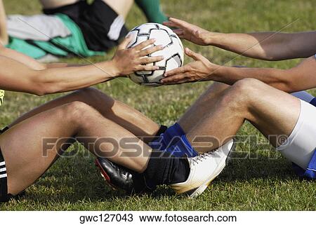 Stock Image - Side profile of two soccer players training with a soccer player. Fotosearch