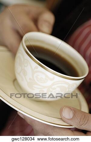Close-up of a person's hand holding a cup of black tea View Large Photo Image Picture - Close-up of a person's hand holding a cup of black tea. Fotosearch