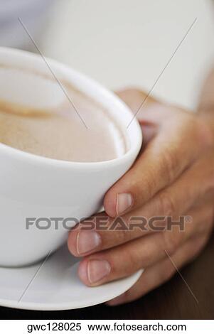 Stock Photography - Close-up of a person's hand holding a cup of coffee. Fotosearch