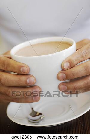 Stock Image - Close-up of a person's hands holding a cup of coffee. Fotosearch