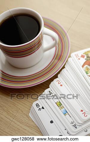 Stock Photo - High angle view of a cup of black tea with playing cards. Fotosearch