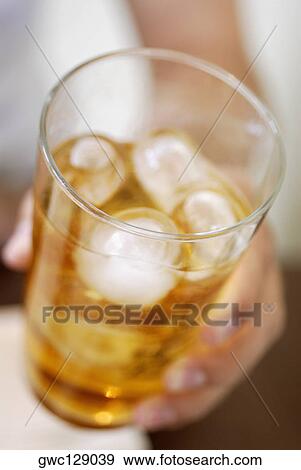 Close-up of a human hand holding a glass of ice tea View Large Photo Image Stock Photo - Close-up of a human hand holding a glass of ice tea. Fotosearch