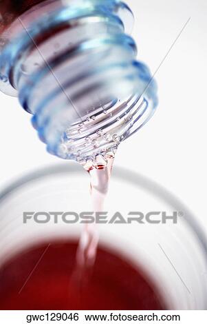 Liquid pouring from a bottle into a glass View Large Photo Image Stock Photograph - Liquid pouring from a bottle into a glass. Fotosearch