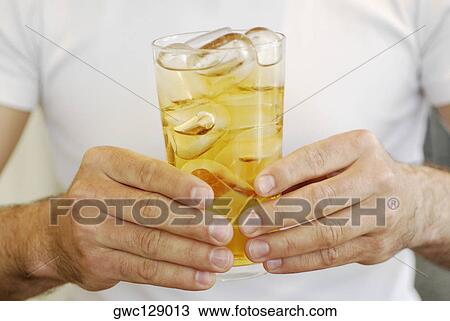 Mid section view of a man holding a glass of whiskey View Large Photo Image Stock Image - Mid section view of a man holding a glass of whiskey. Fotosearch