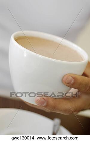 Picture - Close-up of a person's hand holding a cup of coffee. Fotosearch