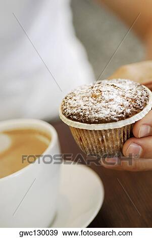 Stock Photo - Close-up of a person's hand holding a cupcake. Fotosearch