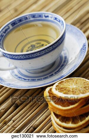 Stock Image - Close-up of lemon slices and a cup of herbal tea. Fotosearch
