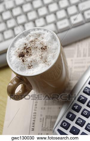 Stock Image - High angle view of a coffee cup with a computer keyboard and a calculator. Fotosearch