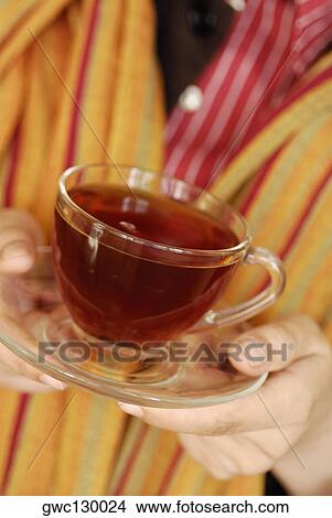 Mid section view of a person holding a cup of black tea View Large Photo Image Picture - Mid section view of a person holding a cup of black tea. Fotosearch