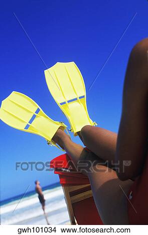Close-up of a woman sitting on the beach wearing flippers, Caribbean View Large Photo Image Picture - Close-up of a woman sitting on the beach wearing flippers, Caribbean. Fotosearch