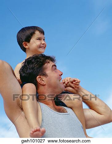 Low angle view of a mid adult man carrying his son on his shoulders, Bermuda View Large Photo Image Stock Photo - Low angle view of a mid adult man carrying his son on his shoulders, Bermuda. Fotosearch