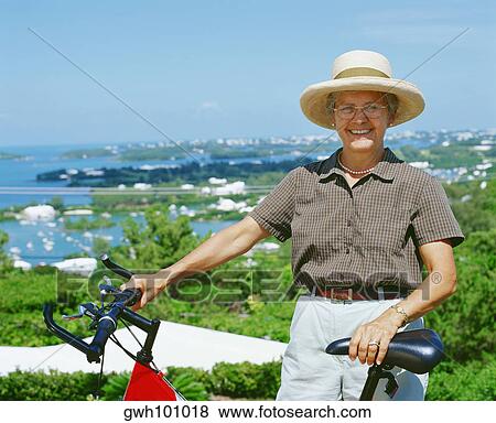 Portrait of a senior woman standing with her bicycle, Bermuda View Large Photo Image Stock Photo - Portrait of a senior woman standing with her bicycle, Bermuda. Fotosearch