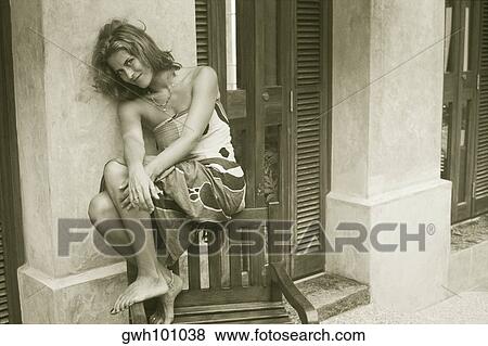 Stock Photo - Portrait of a young woman sitting on a chair. Fotosearch