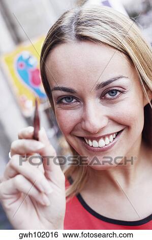 Close-up of a young woman holding a paintbrush and smiling View Large Photo Image Stock Photograph - Close-up of a young woman holding a paintbrush and smiling. Fotosearch
