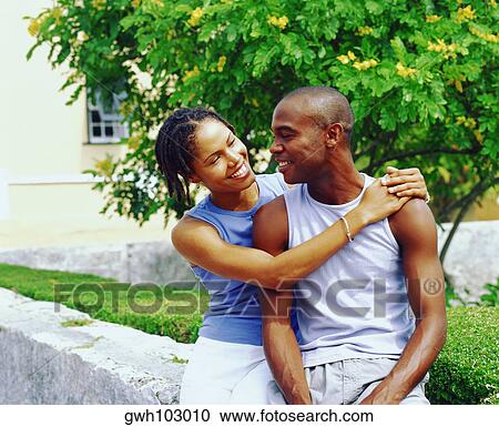 Stock Image - Close-up of a young woman embracing a young man and smiling, Bermuda. Fotosearch