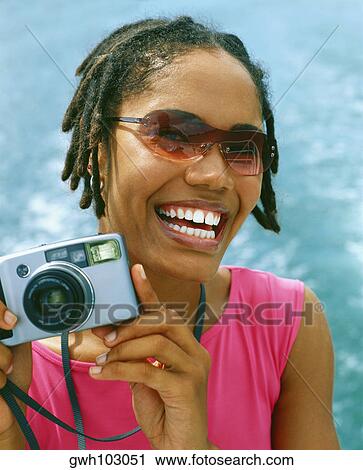 Portrait of a young woman holding a digital camera and smiling, Bermuda View Large Photo Image Stock Image - Portrait of a young woman holding a digital camera and smiling, Bermuda. Fotosearch