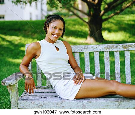 Portrait of a young woman sitting on a bench and smiling, Bermuda View Large Photo Image Stock Photo - Portrait of a young woman sitting on a bench and smiling, Bermuda. Fotosearch