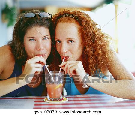 Portrait of two young women drinking juice from a glass with straws, Bermuda View Large Photo Image Stock Photo - Portrait of two young women drinking juice from a glass with straws, Bermuda. Fotosearch