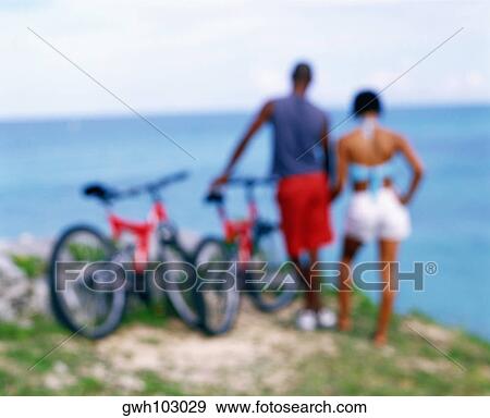 Rear view of a young couple standing with bicycles on the coast, Bermuda View Large Photo Image Stock Photo - Rear view of a young couple standing with bicycles on the coast, Bermuda. Fotosearch
