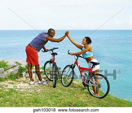 Side profile of a young couple holding hands near bicycles, Bermuda View Large Photo Image Stock Photo - Side profile of a young couple holding hands near bicycles, Bermuda. Fotosearch